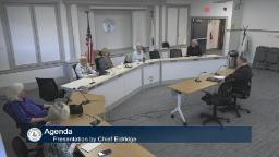 Thumbnail of meeting video is a wide shot showing the entire board and the a person at the presenters table.