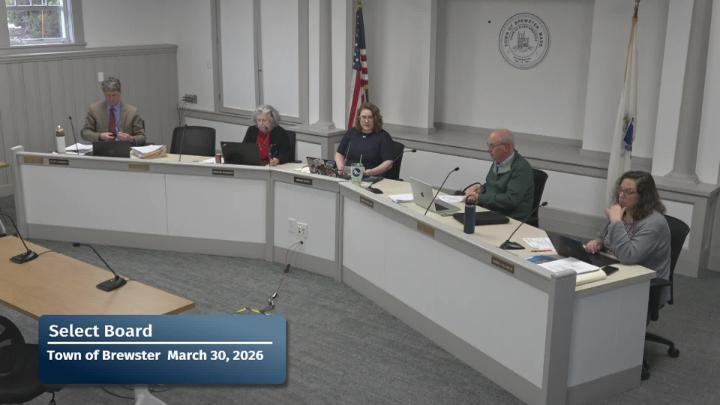 Wide shot of committee members sitting at the large curved meeting table for their meeting.